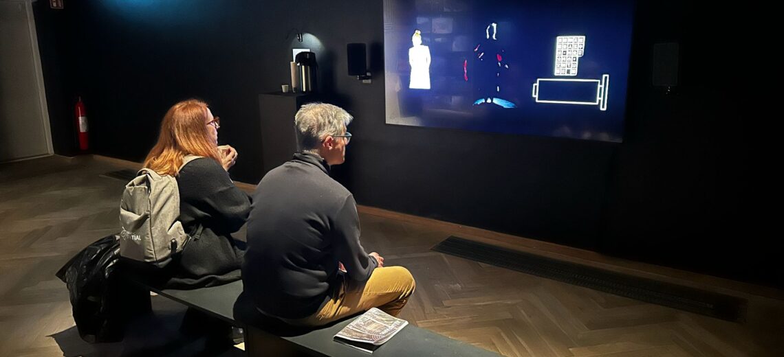 Two people watching a screen in a black box
