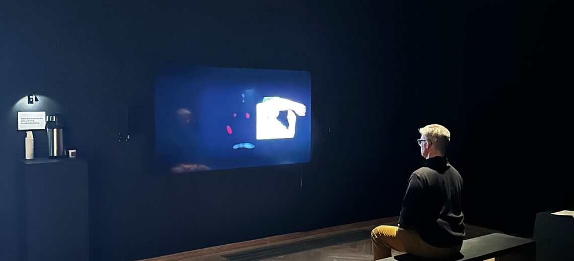 A person sitting in a black box watching a screen