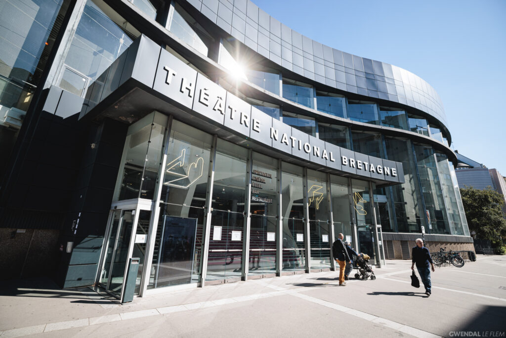 The TNB venue is a large building designed in a contemporary architectural style. Its entrance features glass walls, while the rest of the structure is gray.