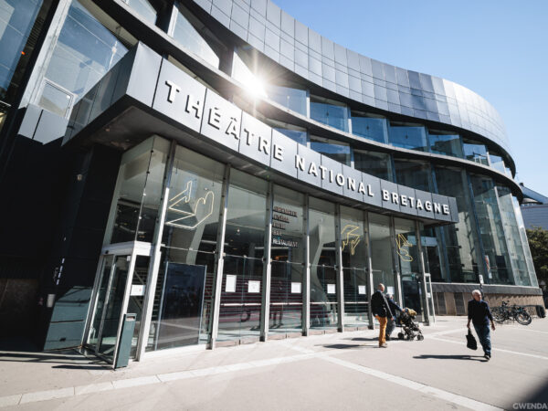The TNB venue is a large building designed in a contemporary architectural style. Its entrance features glass walls, while the rest of the structure is gray.