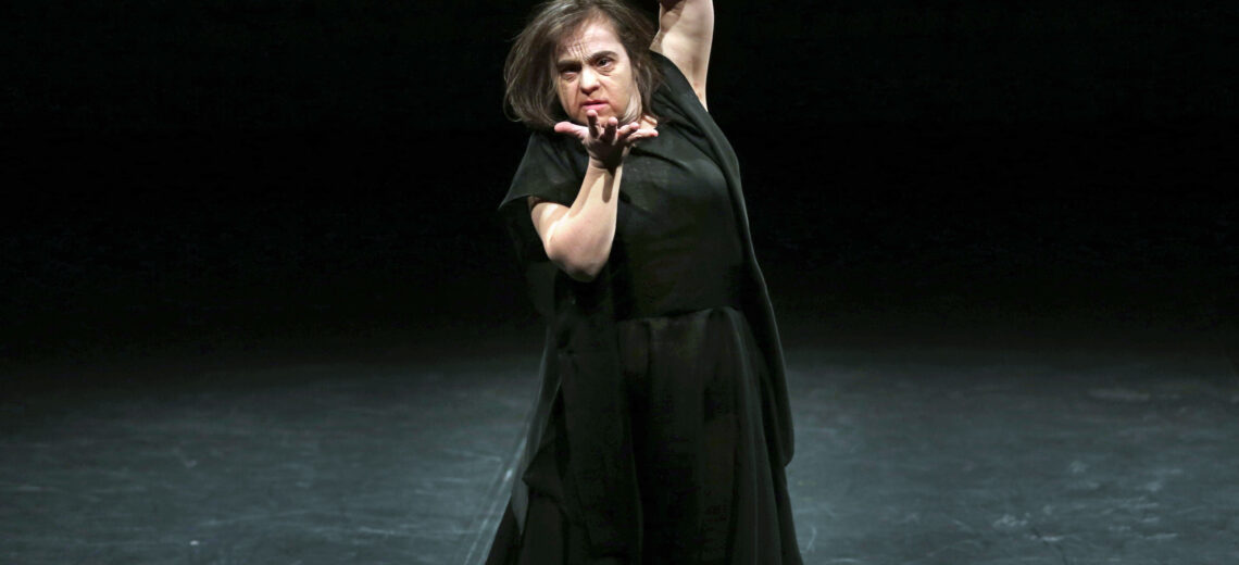 Learning disabled woman in a black outfit dancing expressively