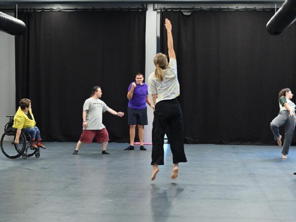 In a dance studio, several performers are reharsing